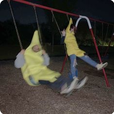 two children swinging on swings at night