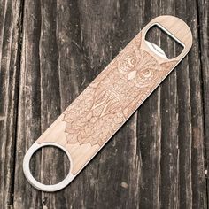 a wooden bottle opener with an owl design on the front and back side, sitting on a wood surface