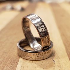 two wedding rings made out of silver coins on top of a wooden table next to each other