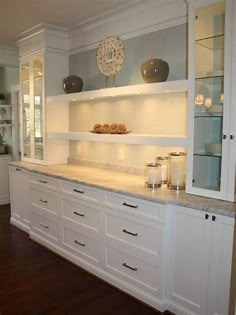 a large kitchen with white cabinets and marble counter tops, along with wood flooring