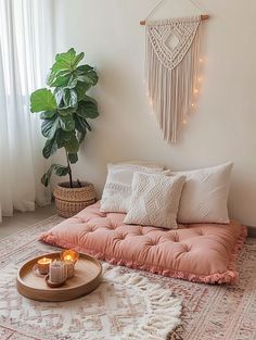 a living room with a pink futon couch and candles on the floor next to a potted plant