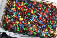 a chocolate cake covered in candy and m & m's on top of a white cloth