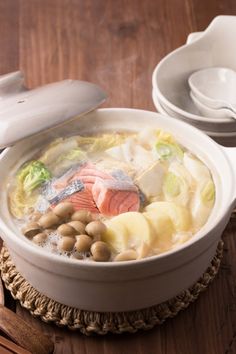 a white bowl filled with soup next to two spoons on top of a wooden table