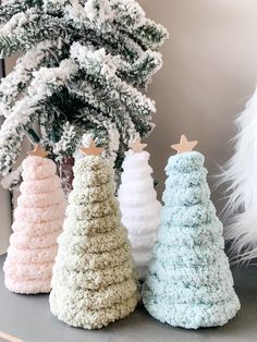 three crocheted christmas trees sitting on top of a table next to a tree