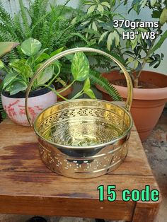 a metal basket sitting on top of a wooden table next to potted greenery