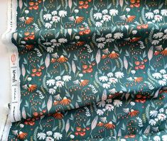 the fabric is green with white and orange flowers on it, along with red berries