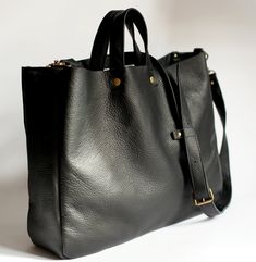 "A large minimal bag on shoulder and hand. Made of black genuine leather. Inside without lining. Dimensions: Height 32 cm (12,6 \"), width 38 cm (15\"), depth about 11 cm (4,3\"), strap detach, length approximately of 130 cm (51\"). Fits A4 and more. Close with two magnetic snaps, detal accessories in the color of old gold. Standard delivery time: European union: 4 - 10 days Europe (not EU): 7 - 14 days U.S.A., Canada: 10 - 20 days Australia, South America, Asia, India, North Africa: 1 - 3 weeks Minimal Bags, Large Leather Bag, Large Leather Tote Bag, Structured Bag, White Tote Bag, Genuine Leather Totes, Large Leather Tote, Everyday Tote, Black Leather Purse