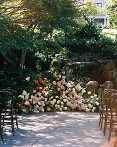 rows of chairs are lined up in the middle of a garden with flowers and greenery