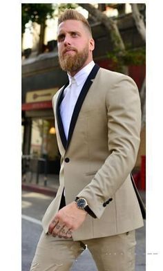 a man with a beard wearing a tan suit and white shirt is walking down the street