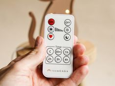 a hand holding a remote control in front of a christmas ornament on the wall