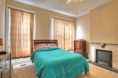 a bedroom with a bed, dresser and fireplace