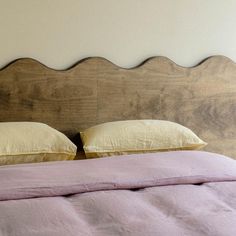 a bed with two pillows on top of it and a headboard made out of wood