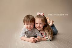 two young children laying on the floor with their arms around each other and smiling at the camera