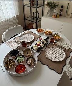 a white table topped with plates and bowls filled with different types of food on top of it