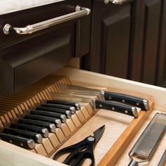 kitchen utensils are organized in a drawer with cutting board and graters