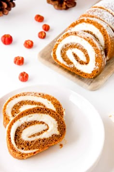 cinnamon roll with icing on a white plate next to some cherry tomatoes and pine cones