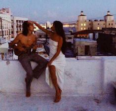 a man and woman sitting on top of a building next to each other