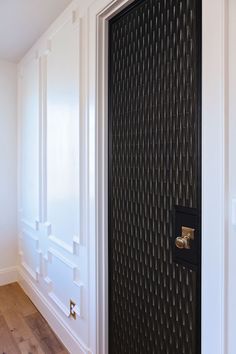 an open door in a white room with wood flooring and wall panels on the walls