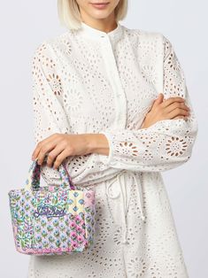 a woman in white dress holding a handbag with flowers on the front and side