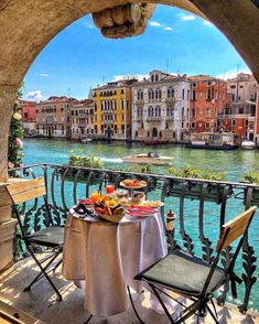 an outdoor table with food on it overlooking the water and buildings in venice, italy