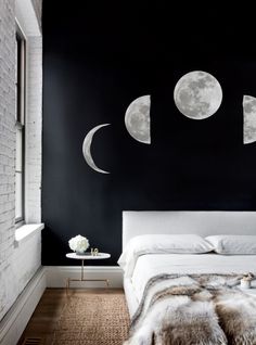 a bedroom with black walls and moon phases on the wall, along with fur rugs