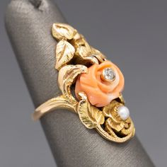 This gorgeous hand-fabricated ring features trailing leaves and vines, featuring a central carved coral with a diamond center. The diamond measures 2.5mm (about 0.06ct). The decor also features a small white pearl. Front front to back she measures about 1 1/8" and it is currently a tiny size 4, though it can be resized for a charge, please ask for a quote in your size before placing your order. The ring is crafted in 14k (acid tested) and weighs a substantial 7.64g. Elegant Coral Ring Jewelry, Vintage Coral Jewelry For Wedding, Coral Vintage Jewelry For Wedding, Vintage Coral Jewelry For Anniversary, Coral Gemstone Jewelry For Weddings, Elegant Coral Jewelry For Anniversary, Coral Vintage Jewelry For Anniversary, Coral Elegant Wedding Rings, Elegant Coral Wedding Rings