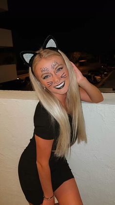 a woman with her face painted to look like a cat is posing for the camera