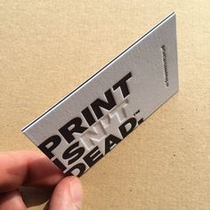 a hand holding a business card that reads print inside the dead