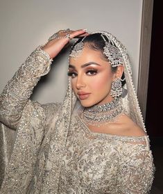 a woman in a wedding dress posing for the camera with her hands on her head