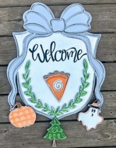 a welcome sign with some decorations around it on a wooden surface and wood planks