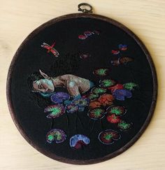 a black embroidered wall hanging with an animal and flowers on it