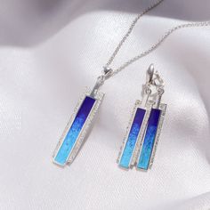 two pendants with blue and white designs on them are sitting on a piece of cloth