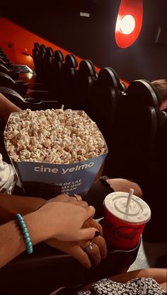 two people are sitting at a table with popcorn and drinks