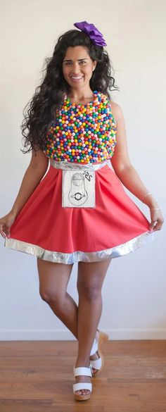 a woman wearing a dress made out of candy balls and smiling at the camera with her hands in her pockets