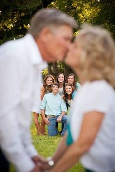 a man kissing a woman's face in front of a group of women and men