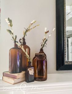 three brown vases sitting on top of a white mantle next to a book and mirror