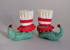 two crocheted boots with red, white and green stripes are sitting next to each other