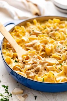 a casserole dish with chicken and noodles in a blue pan on a white table