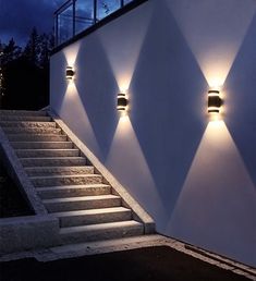 three lights that are on the side of a wall next to some steps and stairs