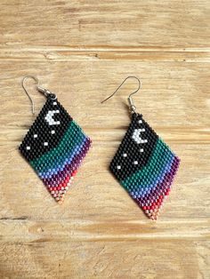 a pair of beaded earrings sitting on top of a wooden table