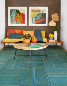 a living room with colorful carpeting and art on the wall behind the couches