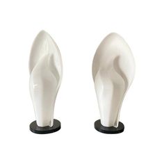 two white ceramic sculptures on black bases, one is shaped to look like an elephant's tail