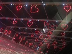 some lights that are hanging from the ceiling and hearts on the wall above them, all lit up