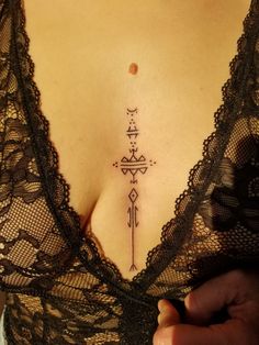 a woman's chest with an arrow tattoo on it