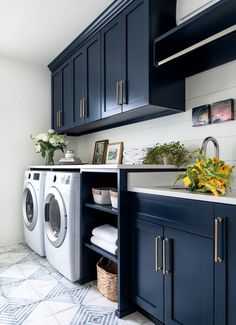 a washer and dryer in a laundry room with blue cabinets, white counter tops and yellow flowers