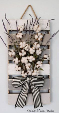 a wooden pallet with cotton flowers and a bow hanging on the front of it