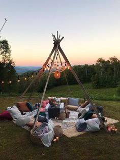 a group of people sitting around a fire pit in the middle of a grassy field