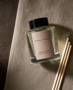 a bottle of perfume sitting next to two chopsticks on a table with a cloth