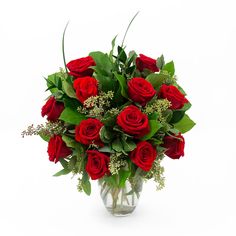 a vase filled with red roses and greenery