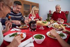 a group of people sitting around a table with plates of food and glasses of wine